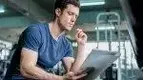 Young-Muscular-Man-Reading-Paper-Notes-In-Gym.webp