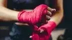 Female-Boxer-wrapping-her-hands-for-a-boxer.webp