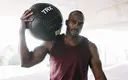 muscular-man-holding-medicine-ball-on-shoulders.webp