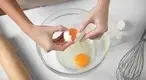 Female-chef-cracking-an-egg.webp