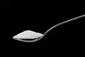 Is Splenda bad for you: Spoon full of sugar on solid black background