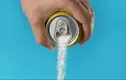 Is Splenda bad for you: Hand holding a soda can and pouring sugar