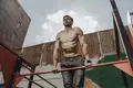 A man does a muscle up as part of a calisthenics workout