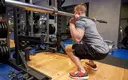 Strong man doing warm up squats with a barbell in the gym.