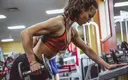 Lean female doing dumbbell rows in a gym