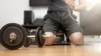 Man wrapping his hands for a home workout with dumbbells and to develop his power