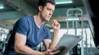 Young-Muscular-Man-Reading-Paper-Notes-In-Gym.