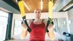 Focused-Bald-Man-Doing-TRX-Recline-Row and TRX accessory exercises for his suspension trainer exercises