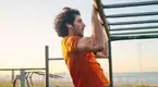 Fit man working out in a playground outdoors doing pull ups on a monkey bars