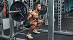 Fitness model doing a barbell back squat exercise