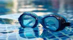 Swimming goggles on a towel next to a pool