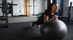 Female performing the stability ball stir to pot exercise in an empty gym