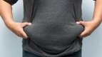 Overweight man holding his body fat while wearing a black shirt