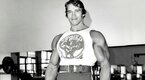 Bodybuilder and former governor of California Arnold Schwarzeneggar smiling in the gym