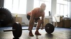 Bald middle aged man performing a medium sumo deadlift to prevent injuries to his knee and back