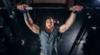 Muscular fit man with a beard focused on pull-up progression in the gym