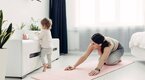 A toddler exporing her surroundings while her mom workouts out while looking on