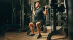 Muscular man performing a smith machine leg workout for leg day at the gym