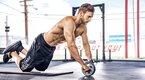 Fitness model working out his ab muscles with ab wheel roll out exercise