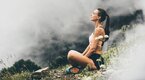 Young healthy female meditating on a foggy hillside