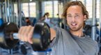 Young fit man performing a dumbbell front raise exercise for his shoulder workout