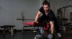 Young fit man performing a single arm bent over row exercise for his 30 minute express workout program