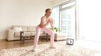 Female-In-Pink-Athletic-Gear-Practicing-Squatting-In-Living-Room-Streaming-Programs