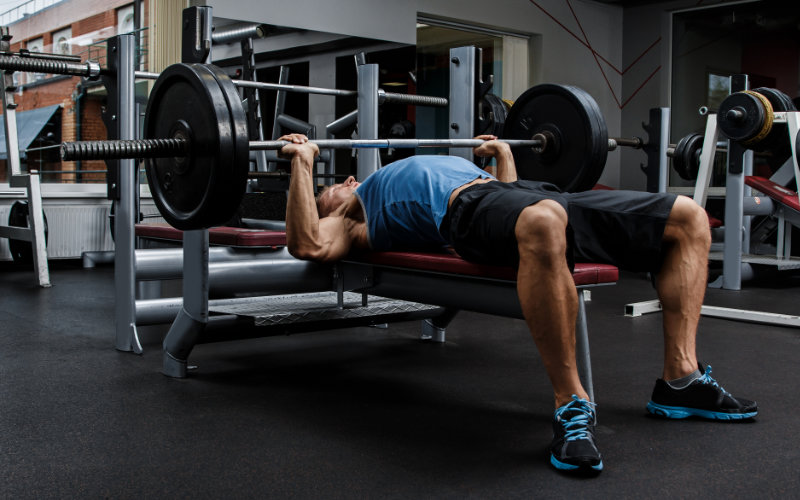 Man doing barbell bench press in gym.