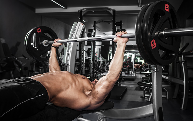 Shirtless muscular man doing heavy bench press in the gym