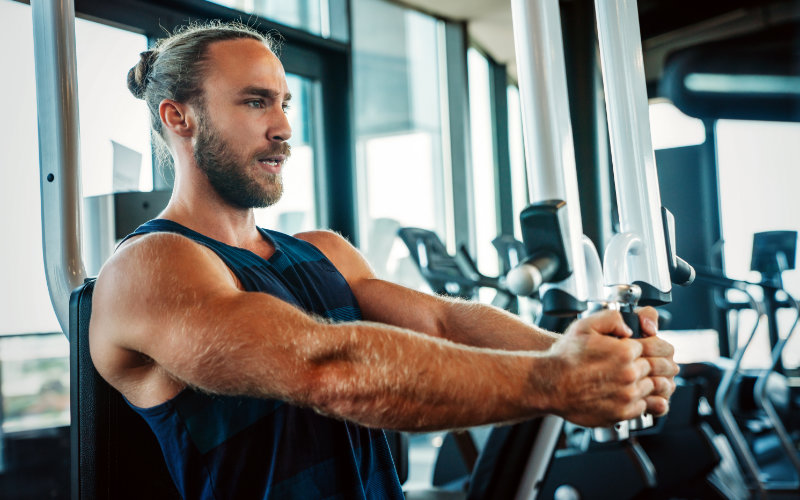 Man doing pec deck machine in gym. 