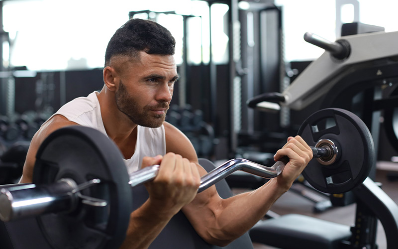 Muscular man doing bicep curls in the gym