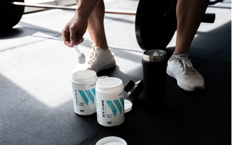 Swolverine athlete scooping beta-alanine into shaker bottle.