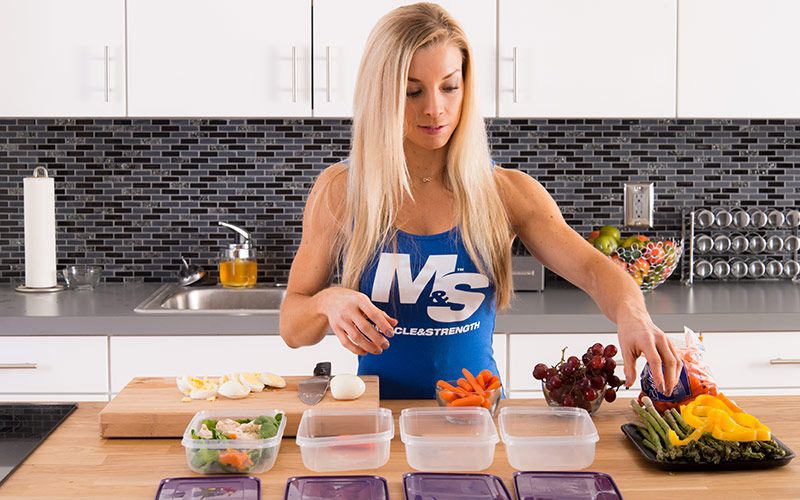 Female Bodybuilder reaching for vegetable and chopping eggs