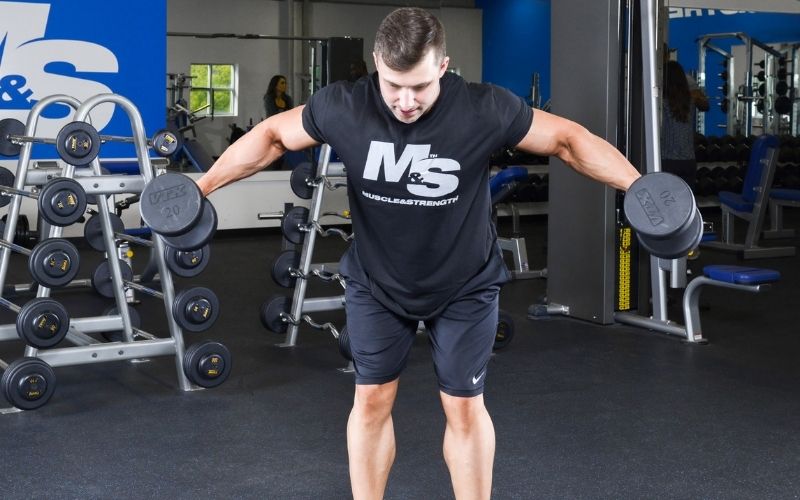 Male athlete wearing a black shirt doing dumbbell rear delt flys in the gym